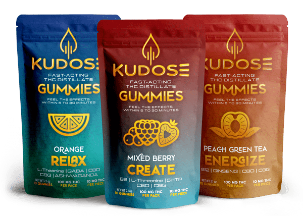 Photograph of three pouches of THC gummies. Each pouch says "Kudose Fast-Acting THC Gummies" Three flavors are present - Relax, Create, and Energize